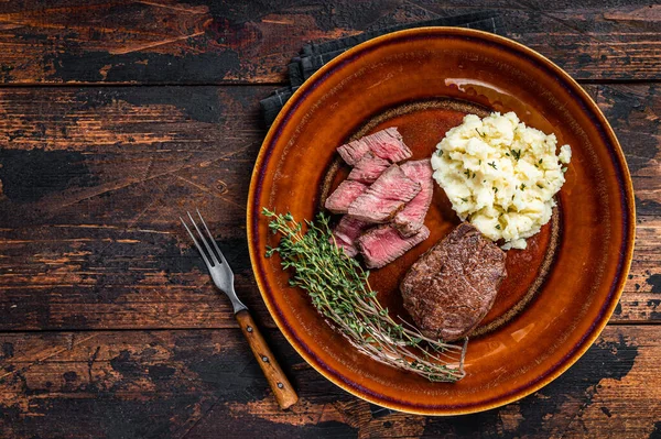 Filetto mignon affettato o filetto di manzo su un piatto rustico con purè di patate. Fondo in legno scuro. Vista dall'alto. Copia spazio — Foto Stock