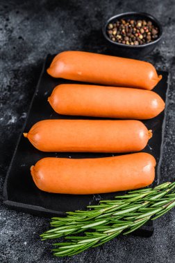 Mermer bir tahtanın üzerinde çiğ sosisli sucuk. Siyah arka plan. en üstteki görünüm