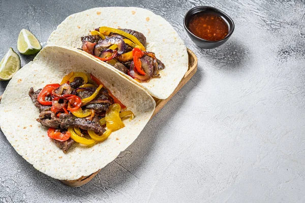 Fajitas con strisce di carne di manzo, peperone colorato e cipolle, servito con tortillas e salsa. Sfondo bianco. Vista dall'alto. Copia spazio — Foto Stock