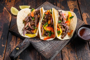 Domuz eti, soğan, domates, tatlı biber ve salsa soslu taco kabuğu. Meksika yemeği. Koyu ahşap arka plan. Üst görünüm