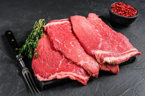 Rohes Rindfleisch rundes Steak auf einem Marmorbrett. Schwarzer Hintergrund. Ansicht von oben — Stockfoto