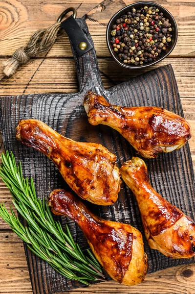 Barbecue roasted chicken drumsticks on a wooden cutting board. wooden background. top view — Stock Photo, Image