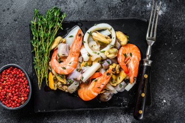 Karides, karides, midye, mürekkep balığı ve ahtapotla taze deniz ürünleri karışımı. Siyah arka plan. Üst görünüm