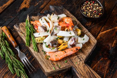 Çiğ deniz ürünleri kokteyli karides, karides, midye, mürekkep balığı ve ahtapotla karıştırılmış. Koyu ahşap arka plan. Üst görünüm