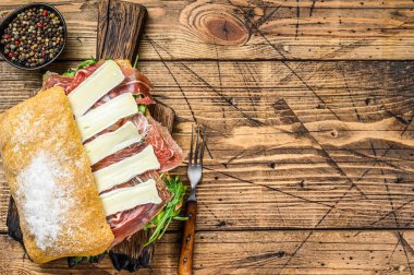 Ciabatta ekmekli Parma Jambonlu Sandviç roka ve peynirli Camembert peyniri. Ahşap arka plan. Üst Manzara. Boşluğu kopyala