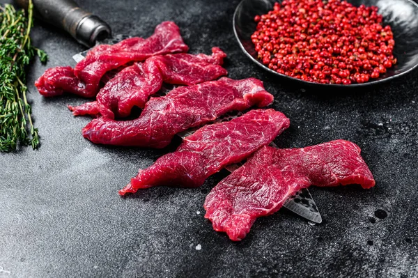 Fresh beef marbled meat cut into thin strips for goulash. Black background. Top view