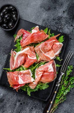 Misket tahtasında dilimlenmiş Jamon Serrano domuz eti. Siyah arka plan. Üst görünüm