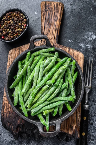 Bevroren groene bonen in een pan. Zwarte achtergrond. bovenaanzicht — Stockfoto