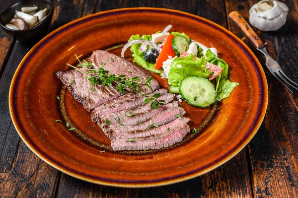 Hacher le steak de viande de veau grillé dans une assiette avec salade. Fond en bois foncé. Vue du dessus — Photo