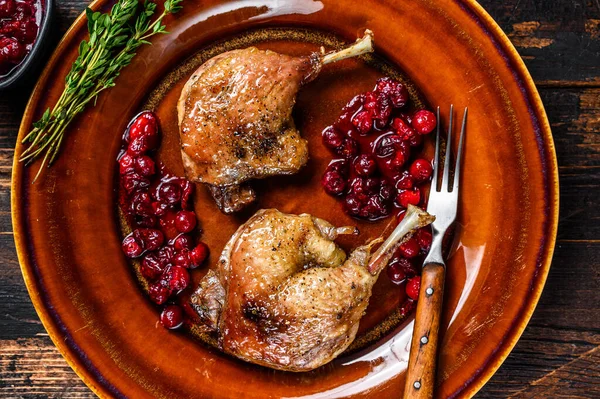 Weihnachtsgebratene Entenkeulen mit Preiselbeersoße. Dunkler Holzhintergrund. Ansicht von oben — Stockfoto