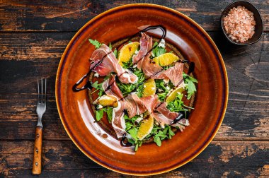 Jambonlu salata, parmesan peyniri, roka ve mandalina. Karanlık ahşap arka plan. Üst görünüm