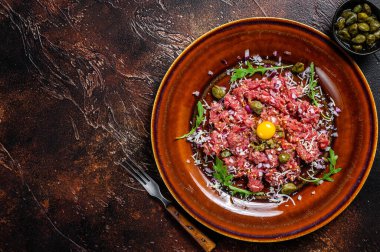 Çiğ yumurta sarısı, turşu ve parmesan peynirli biftek tartar. Karanlık arka plan. Üst Manzara. Boşluğu kopyala