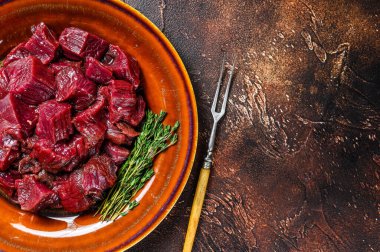 Tabakta bir gulaş için çiğ geyik eti. Karanlık arka plan. Üst Manzara. Boşluğu kopyala