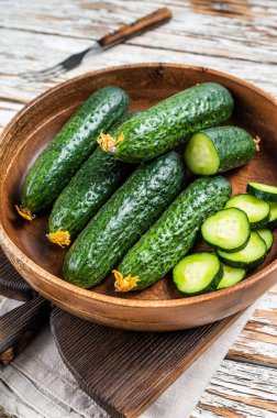 Tahta bir tabakta çiğ organik salatalık. Beyaz tahta arka plan. Üst görünüm