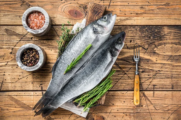 Tahta kesme tahtasının üzerinde biberiyeli taze deniz ürünü. Ahşap arka plan. Üst görünüm