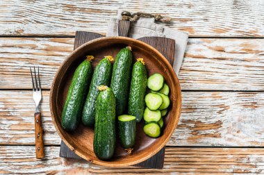 Tahta bir tabakta çiğ organik salatalık. Beyaz tahta arka plan. Üst görünüm