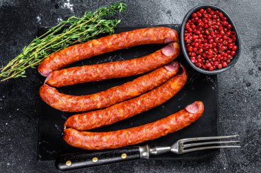 Mermer bir tahtanın üzerinde füme sosis. Siyah arka plan. Üst görünüm