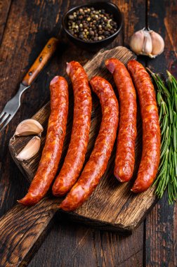 Taze aromatik otlar ve baharatlarla birlikte sıcak füme sosis. Koyu ahşap arka plan. Üst görünüm