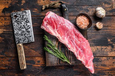 Kısa bir kaburga ve kasap bıçağıyla çiğ et. Koyu ahşap arka plan. Üst görünüm