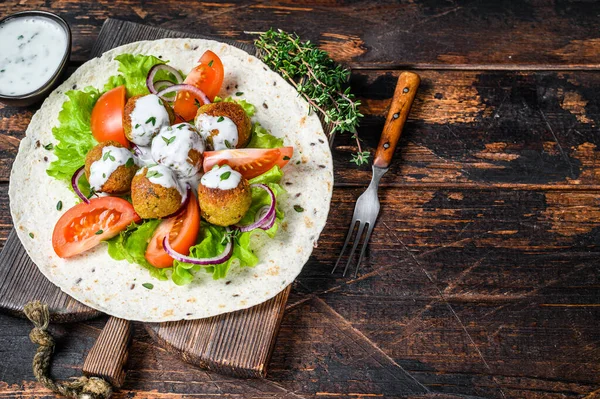 Vegetarische falafel met groenten en tzatziki saus op een tortilla brood. Donker houten achtergrond. Bovenaanzicht. Kopieerruimte — Stockfoto