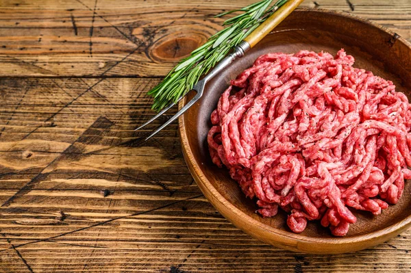Çiğ kıymalı kuzu eti, tabakta otlu kuzu eti. Ahşap arka plan. Üst Manzara. Boşluğu kopyala