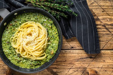 Pesto soslu makarna, taze ıspanak ve tavada parmesan. Ahşap arka plan. Üst Manzara. Boşluğu kopyala