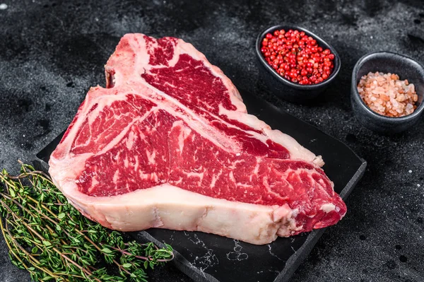 Sušené zrání Syrové T-bone nebo porterhouse hovězí maso Steak s bylinkami a solí. Černé pozadí. Horní pohled — Stock fotografie