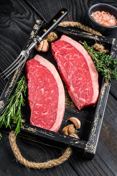 Rauwe Braziliaanse picanha biefstuk of top sirloin rundvlees biefstuk in een houten dienblad. Zwarte houten achtergrond. Bovenaanzicht — Stockfoto