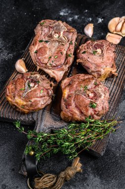 Ahşap bir tahtanın üzerinde ızgara kuzu eti ve otlar. Siyah arka plan. Üst görünüm