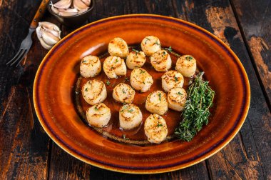 Tabakta tereyağlı baharat soslu kızarmış istiridye. Koyu ahşap arka plan. Üst görünüm