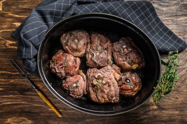 Tavada pişmiş kuzu eti ve şifalı otlar. Ahşap arka plan. Üst görünüm