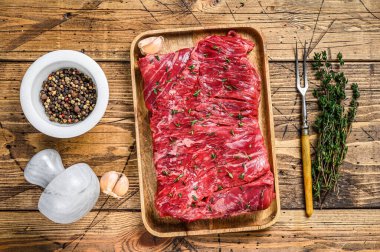 Çiğ et yuvarlak, ahşap tepside otlarla kesilmiş et. Ahşap arka plan. Üst görünüm