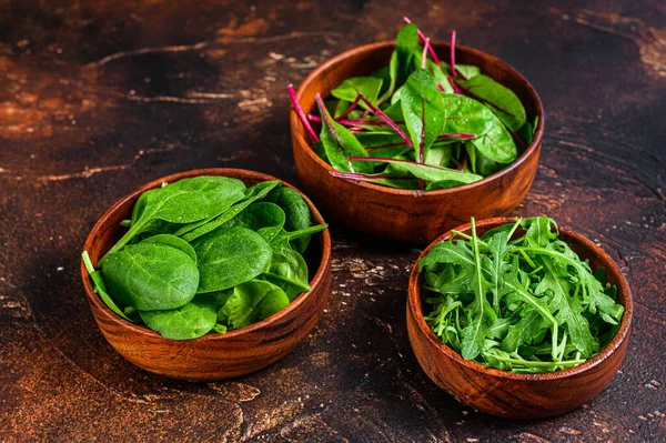 Misture folhas de salada, Arugula, Espinafre e swiis Chard em tigelas de madeira. Fundo escuro. Vista superior — Fotografia de Stock