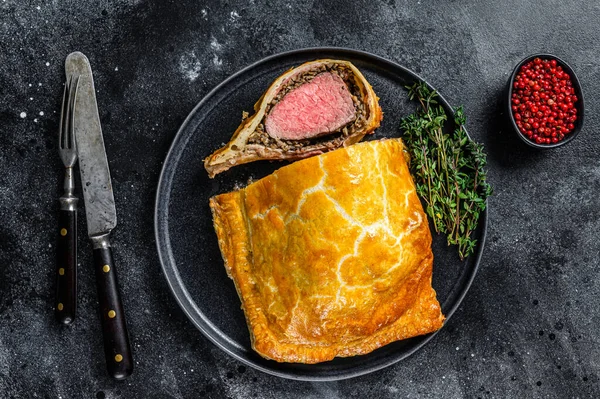 Beef Wellington classic steak dish with tenderloin meat on a plate. Black background. Top view — Stock Photo, Image