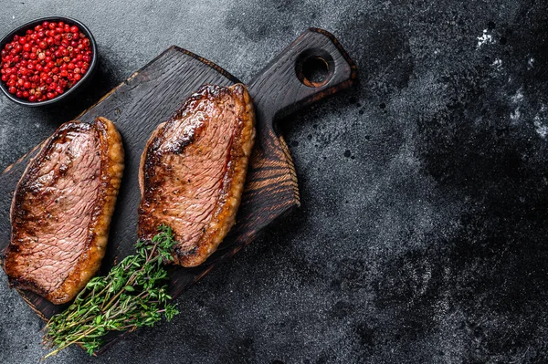 Grillad topp sirloin mössa eller picanha biff på en trä skärbräda. Svart bakgrund. Högst upp. Kopiera utrymme — Stockfoto