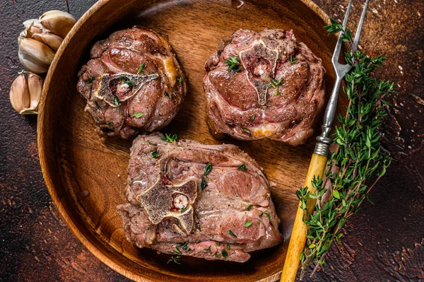 Fried lamb neck meat steaks in a wooden plate with herbs. Dark background. Top view — Stock Photo, Image