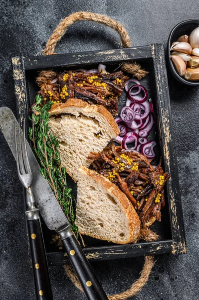 Pulled pork Sandwich with smoked pork meat in a wooden tray. Black background. Top view