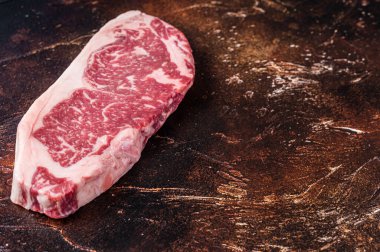 Çiğ New York bifteği ya da kasap masasında striploin. Karanlık arka plan. Üst Manzara. Boşluğu kopyala