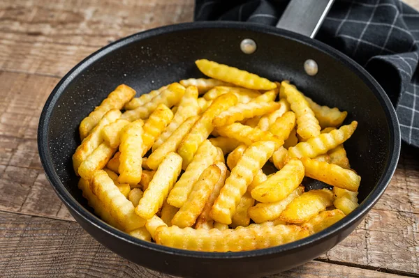 Frites froissées frites pommes de terre bâtonnets dans une casserole. Fond en bois. Vue du dessus — Photo