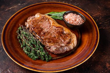 Kızarmış New York bifteği ya da kırsal bir tabakta striploin. Karanlık arka plan. Üst görünüm