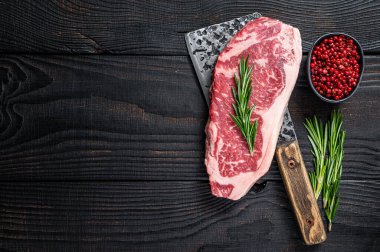 Bir kasap satırında taze çiğ New York bifteği. Siyah ahşap arka plan. Üst Manzara. Boşluğu kopyala