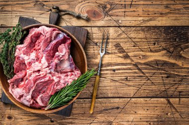 Kemiksiz çiğ koyun eti, ahşap tabakta, otlu omuz eti. Ahşap arka plan. Üst Manzara. Boşluğu kopyala