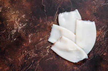 Mutfak masasında çiğ mürekkep balığı veya kalamar tüpleri. Karanlık arka plan. Üst Manzara. Boşluğu kopyala