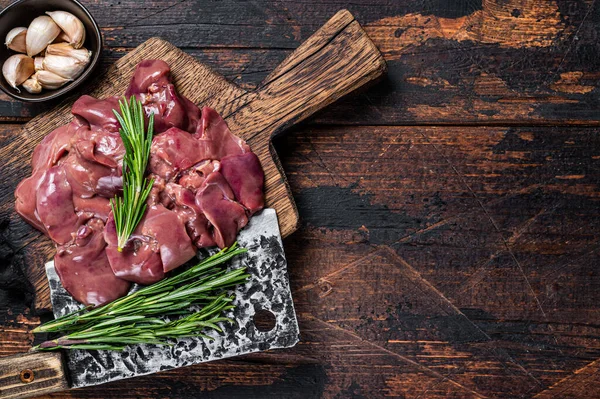 Raw liver chicken offals meat on a wooden cutting board with butcher cleaver. Dark wooden background. Top view. Copy space — Stock Photo, Image