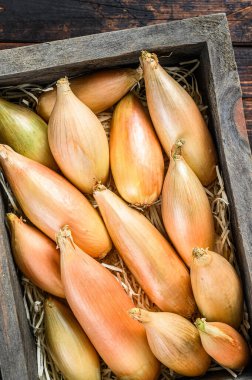 Tahta bir pazar kutusunda çiğ Shallot soğanı soğanı. Karanlık ahşap arka plan. Üst görünüm