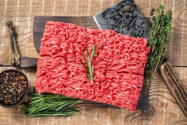 Vers rauw gehakt vlees op een slagersnijplank met hakmes. Houten achtergrond. Bovenaanzicht — Stockfoto