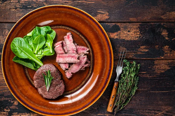 Filet Mignon rôtir et couper les steaks de bœuf dans une assiette avec salade. Fond en bois foncé. Vue de dessus. Espace de copie — Photo