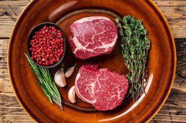 Köy tabaklarında çiğ fileto mignon fileto biftekli biftek. Ahşap arka plan. Üst görünüm