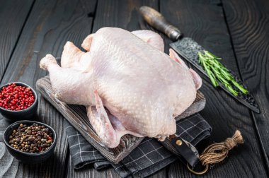 Çiğ tavuk, ahşap bir tahtanın üzerinde otlarla birlikte kümes hayvanları. Kara tahta arka plan. Üst görünüm