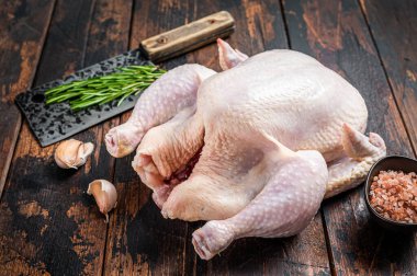 Bütün tavuk, et satırıyla kasap masasında çiğ kümes hayvanları. Karanlık ahşap arka plan. Üst görünüm